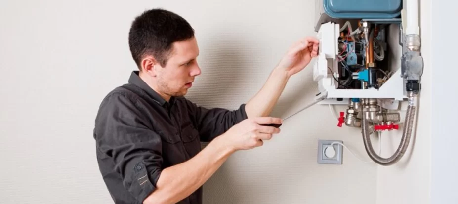 Technician inspecting and repairing a home heating unit using a screwdriver.